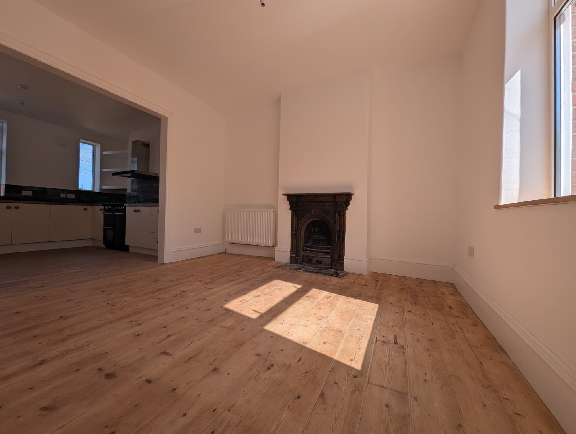 Restored living room with a period cast-iron fireplace and freshly sanded pine floorboards
