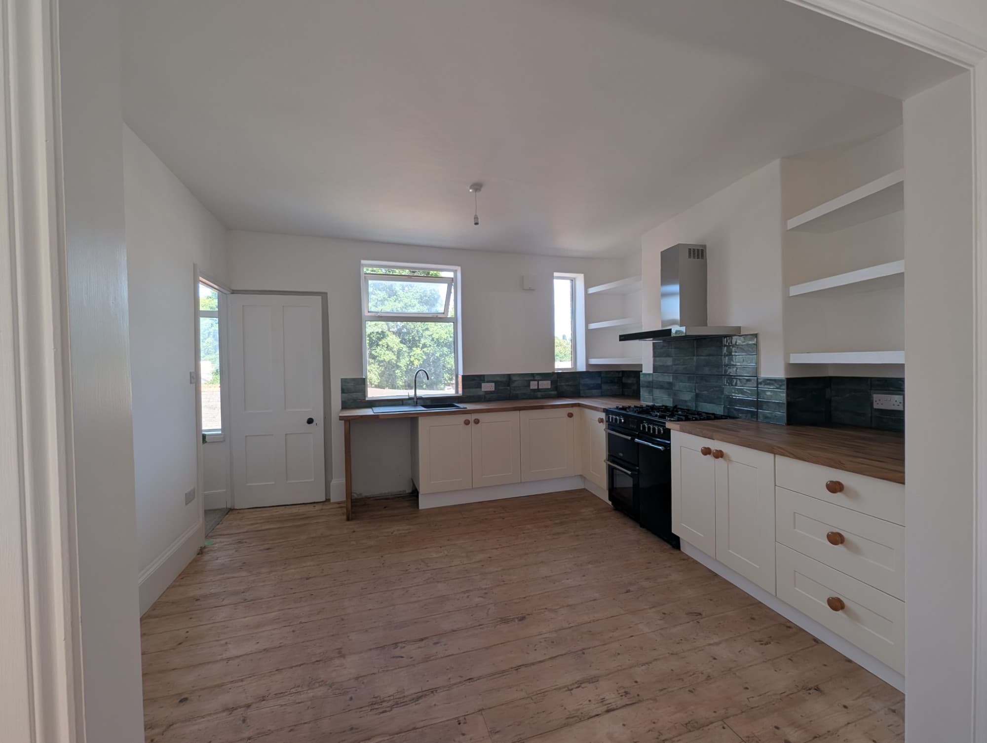 Full kitchen refit showing open shelving, larder cupboards and range cooker