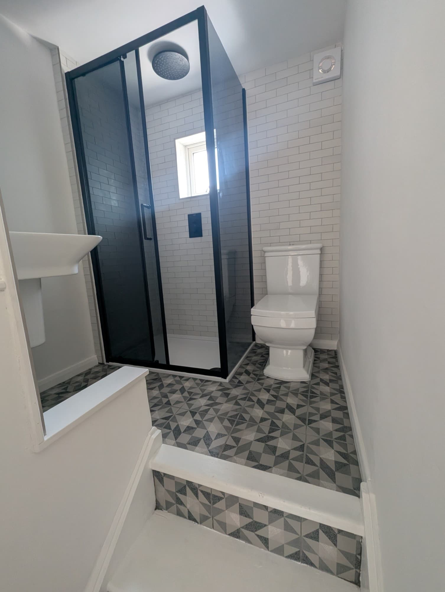 Finished bathroom refit with rainfall shower, close-coupled toilet and patterned floor
