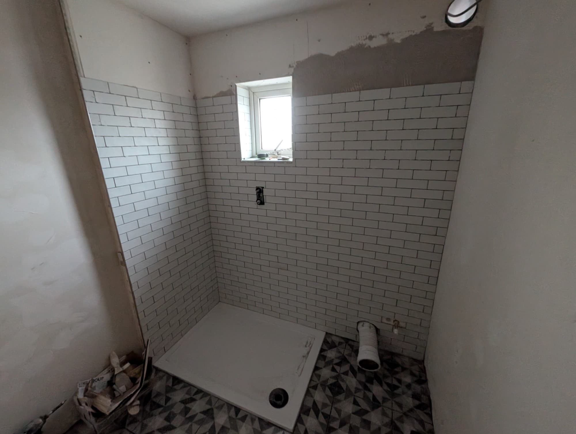 Bathroom during installation - freshly tiled subway walls and shower tray ready to fit