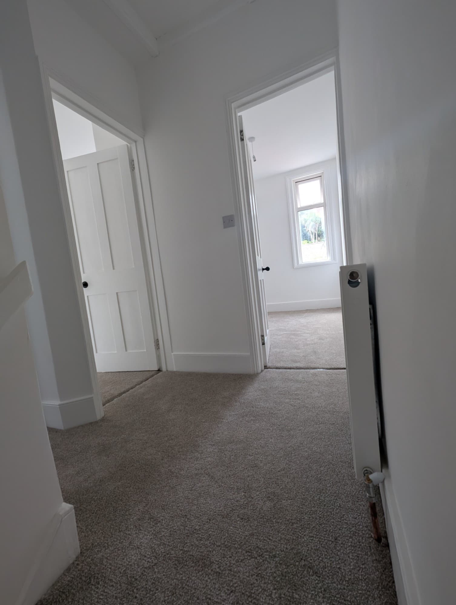 Redecorated hallway with white walls, fresh trim and new neutral carpet